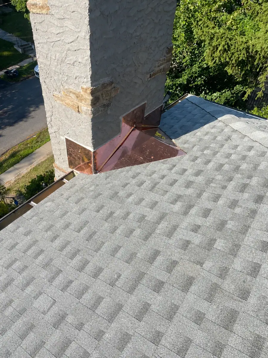 Custom copper chimney cricket installed to redirect water away from the chimney